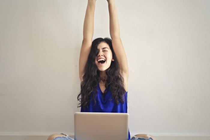 A woman raising her arms straight over her head.