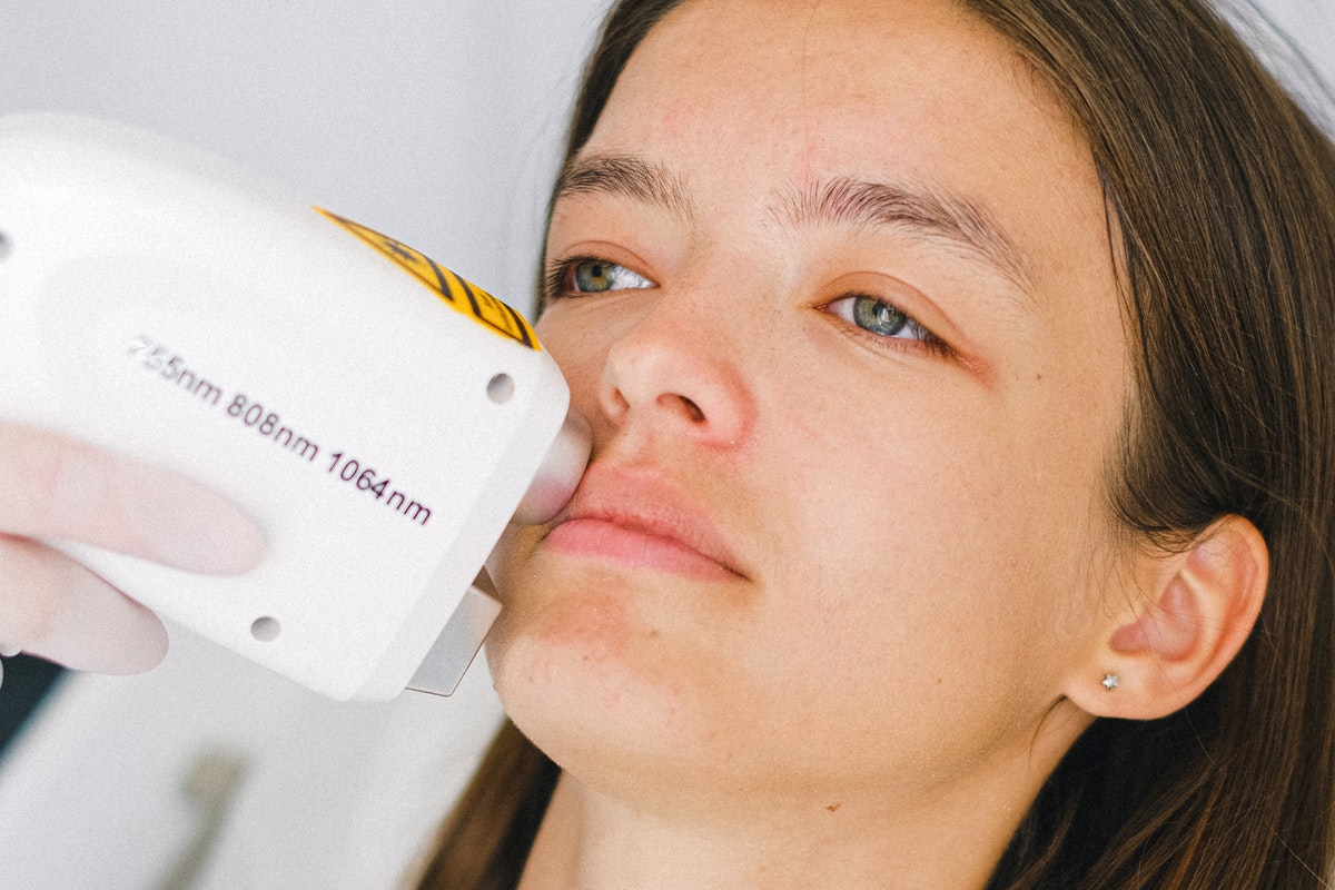 A woman having a laser hair removal treatment on her face.