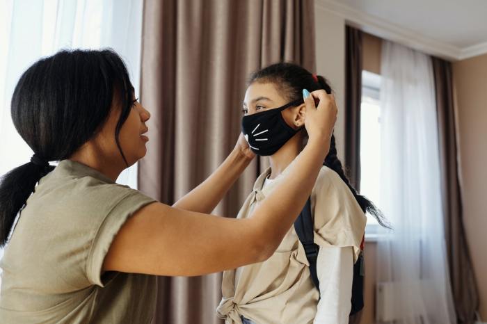 A mom putting a mask on her child.