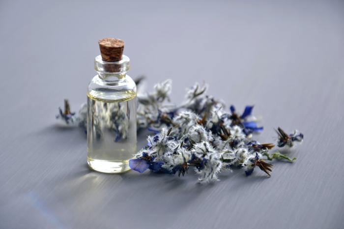A bottle of fragrance and some flowers on a table.