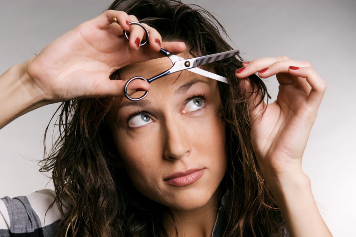 A woman cutting her own bangs.