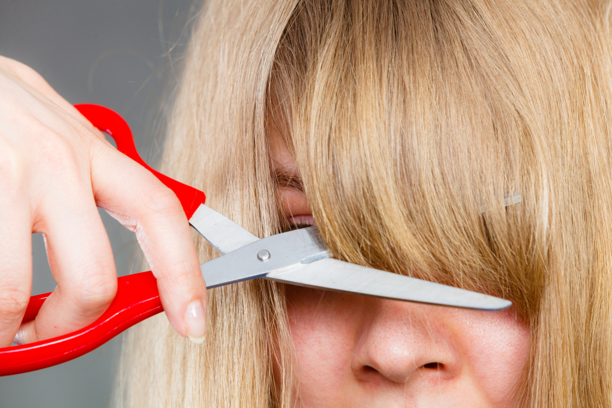 A woman cutting her own bangs.