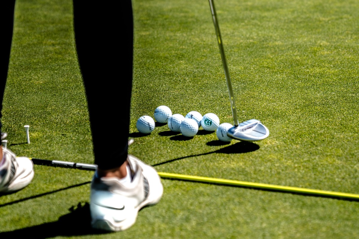 woman-in-white-sneakers-golfing-on-tee