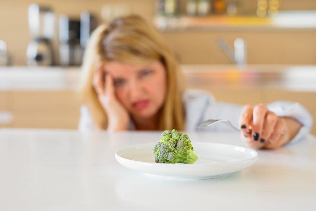 woman upset one piece of broccoli on plate