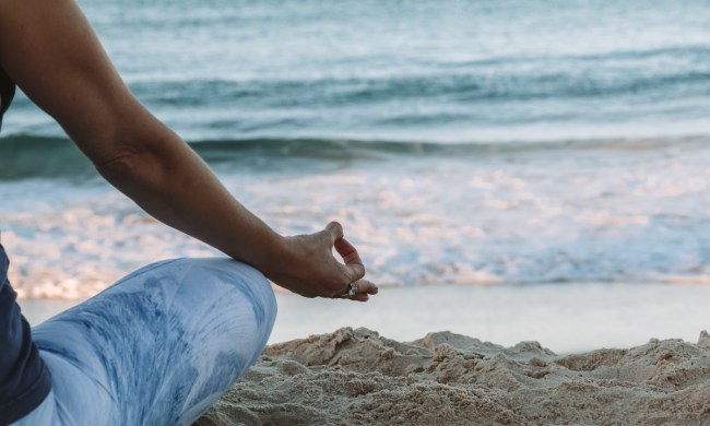 a person meditating in the sand by the ocean