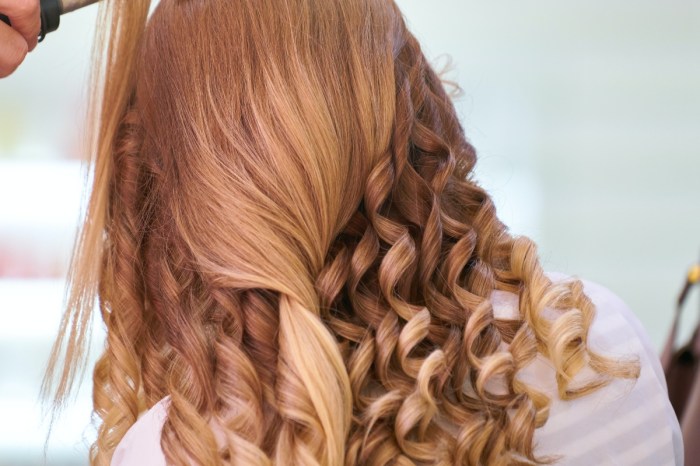 woman using a curling tool to curl her hair