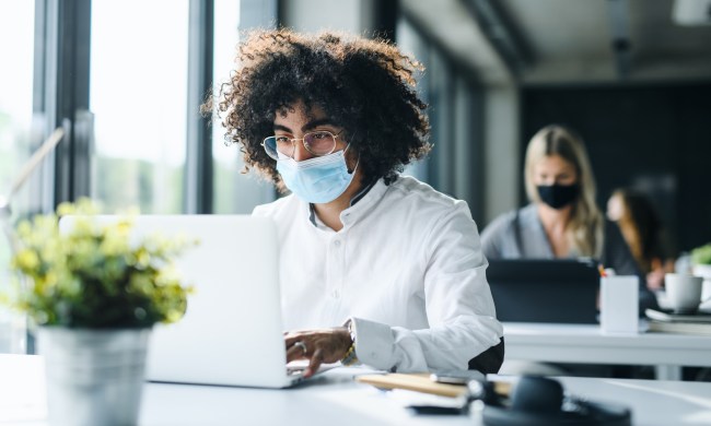 Man wearing mask working at office computer
