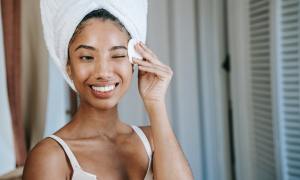 A woman cleaning her face with a face pad and toner.