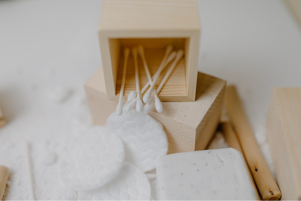 q-tips in a wooden box next to cotton facial pads