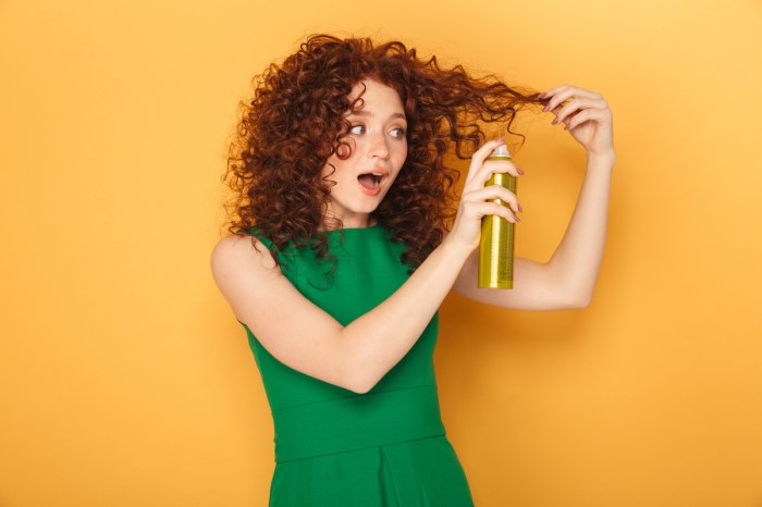 A woman with curly hair spraying product in her hair.