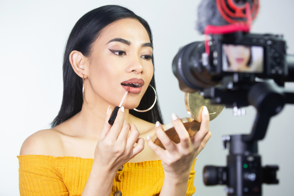 A woman putting on makeup in front of a camera.