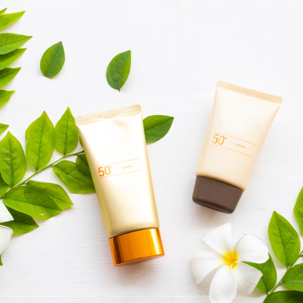 Sunscreen on a table with some green leaves.