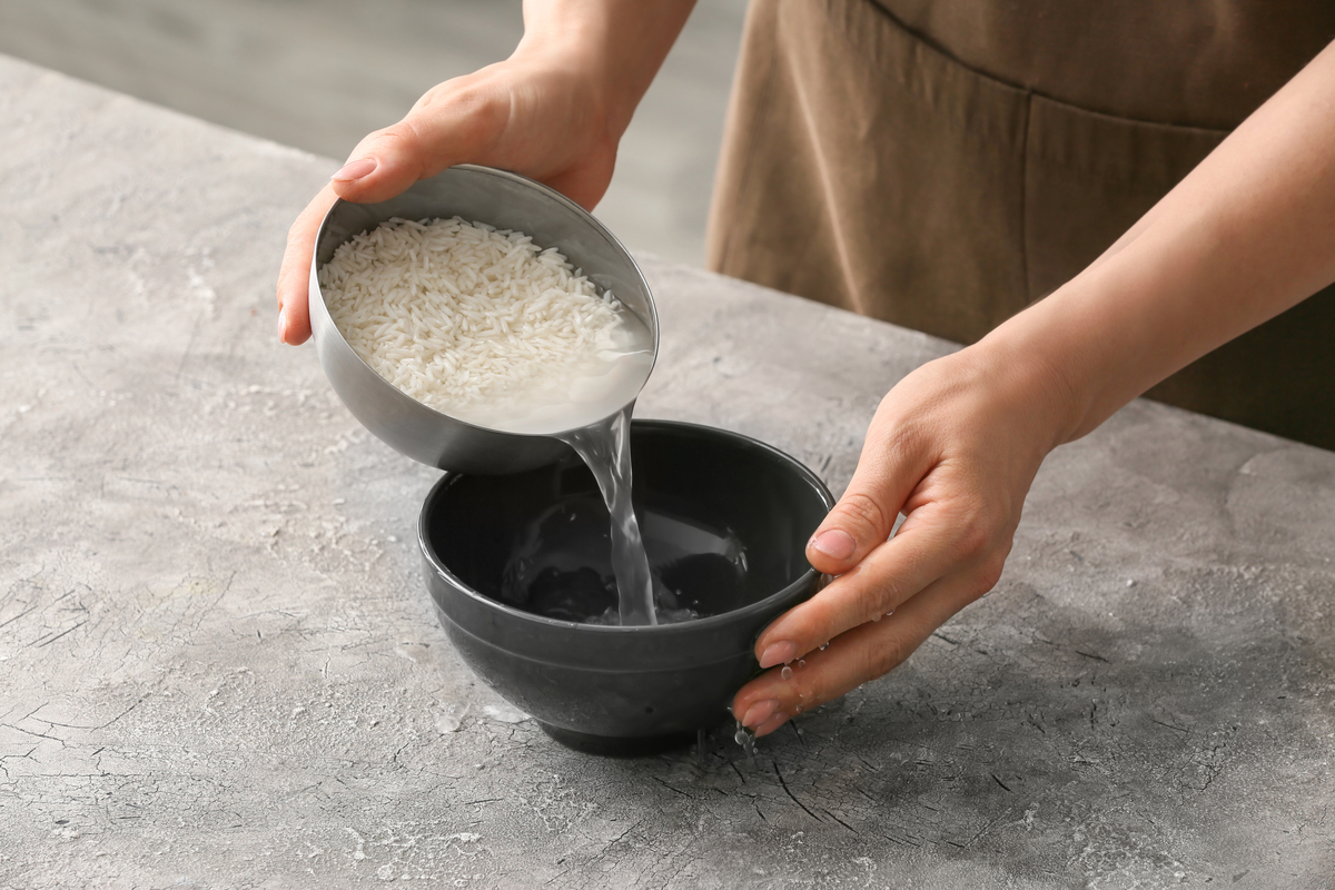 A woman pouring the water out of a rice and water mixture.