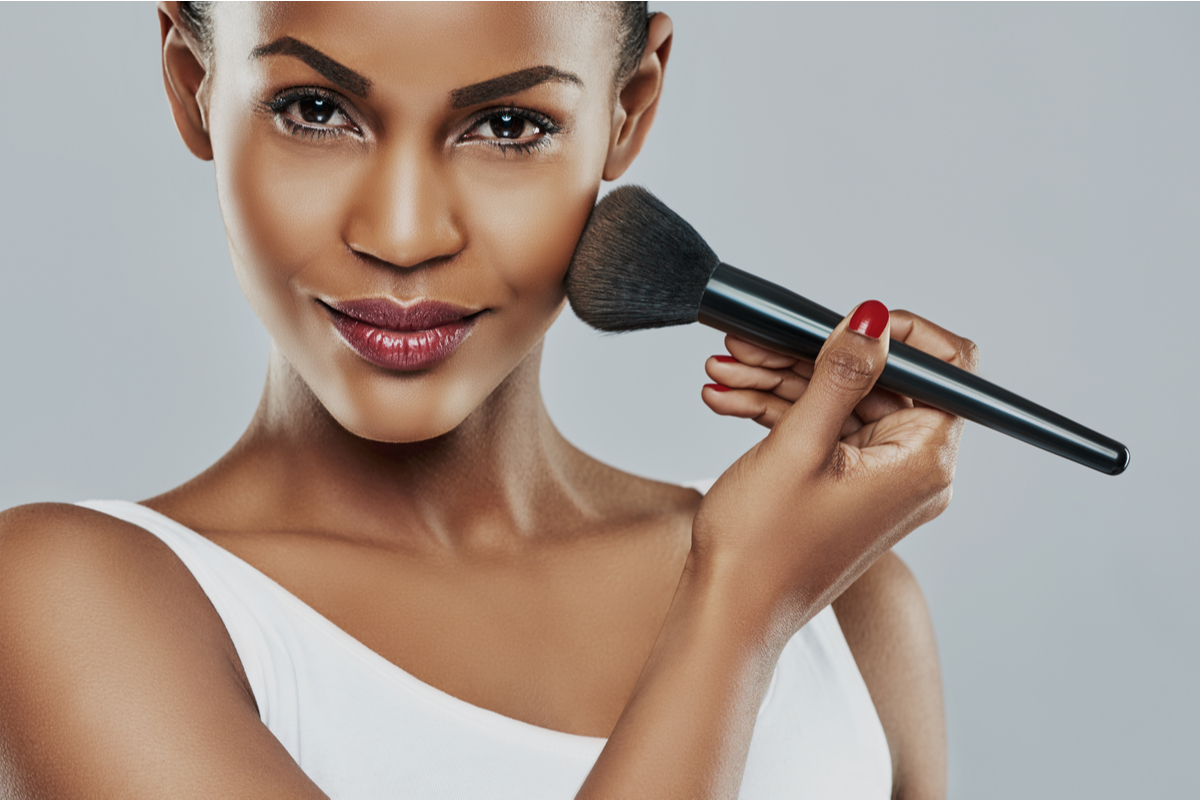 A Black woman applying makeup.
