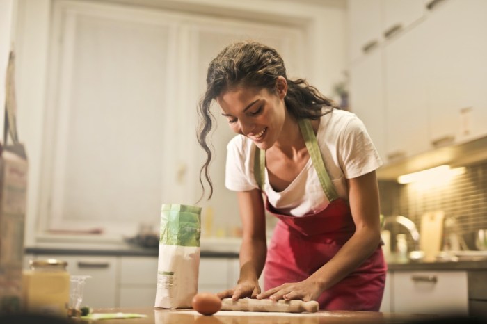 woman with red apron using rolling pin in kitchen