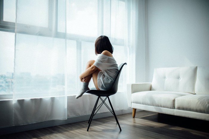 woman looking out window while sitting in chair