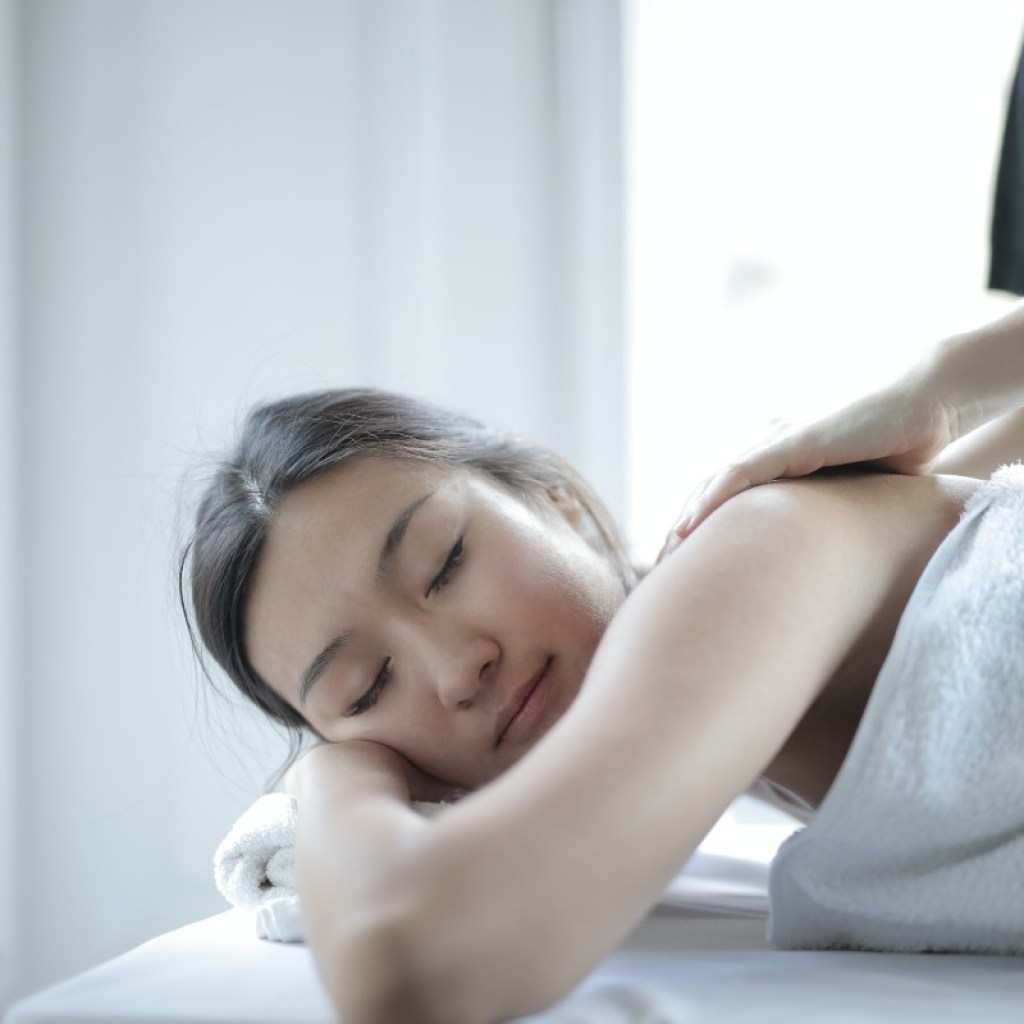 woman receiving upper body treatment while lying in a towel