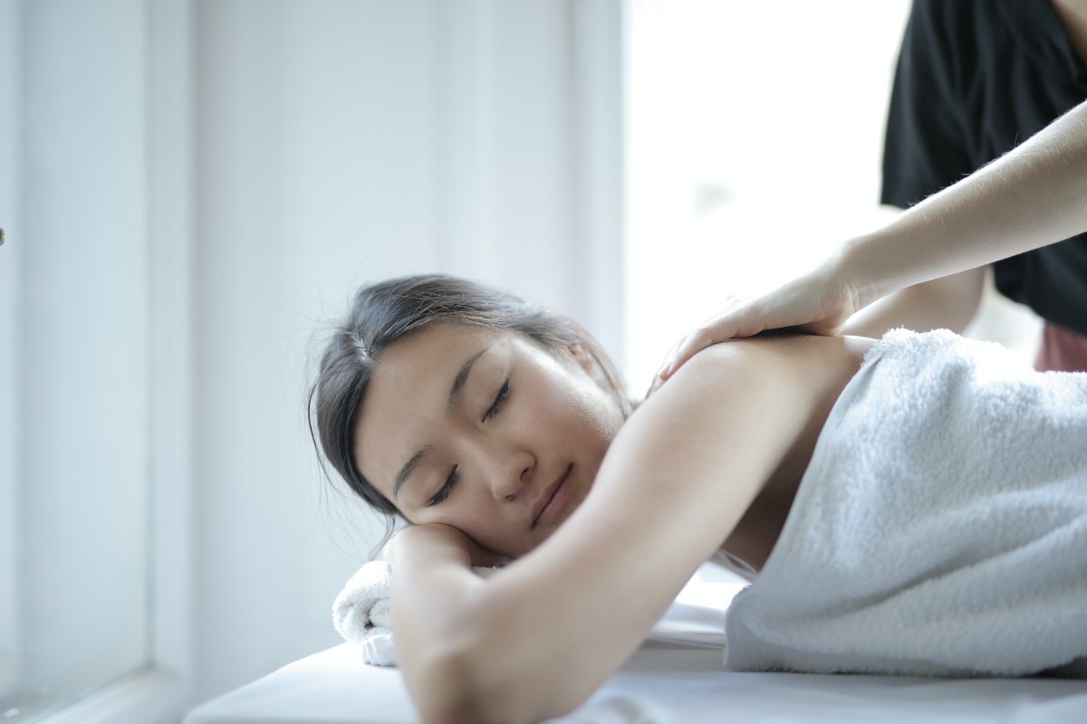 woman receiving upper body treatment while lying in a towel