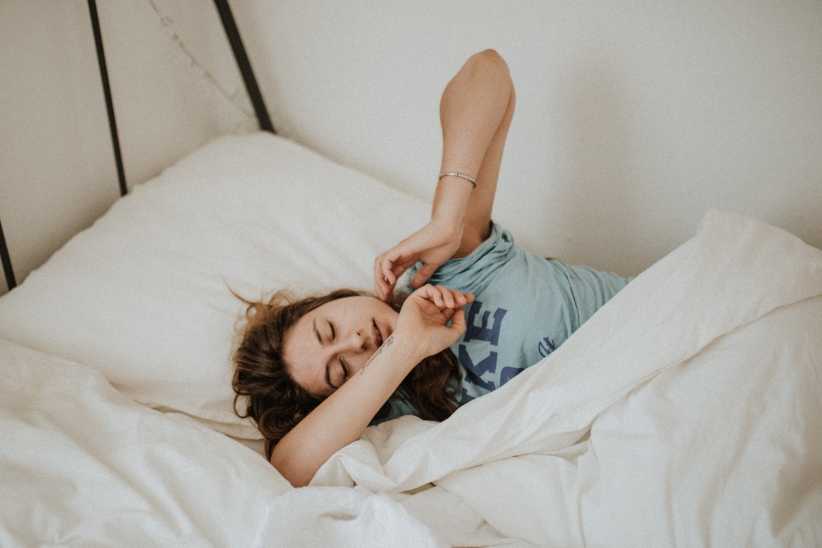 a woman sleeping towards the edge of the bed in a blue shirt
