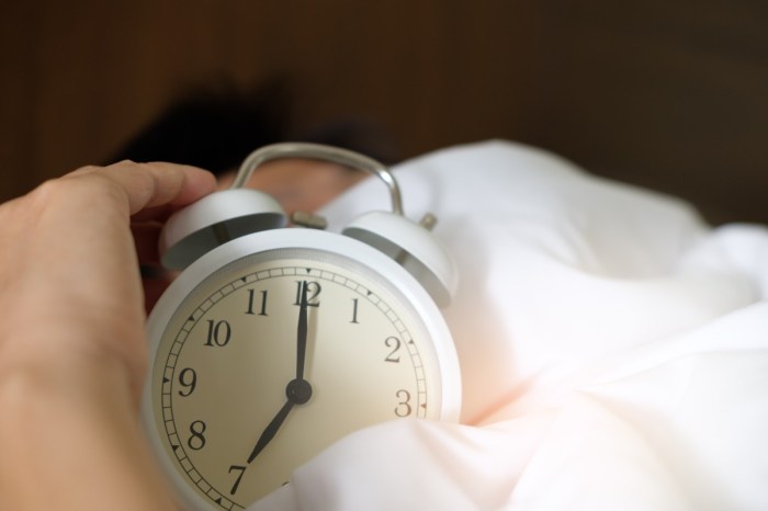 a standard alarm clock in a bed with white sheets