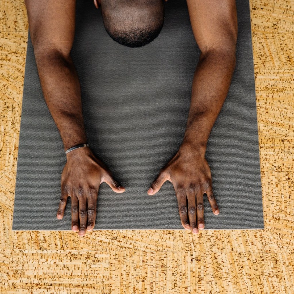 a man in child's pose on a black yoga mat