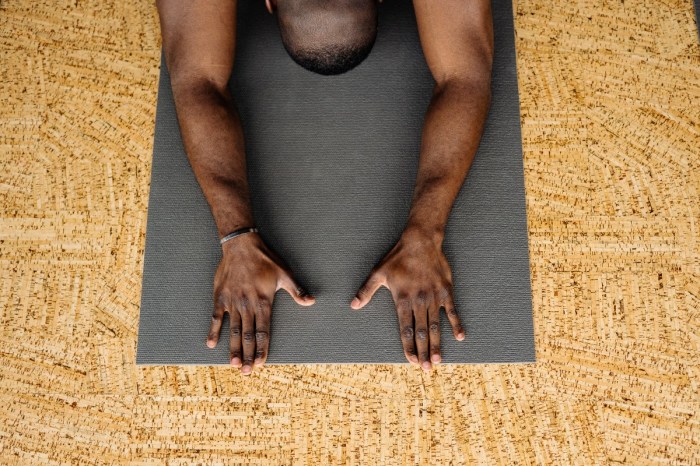 a man in child's pose on a black yoga mat