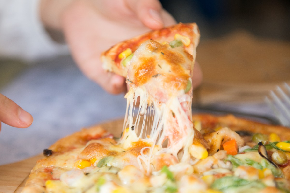 a person taking a slice of pizza with pepper on top