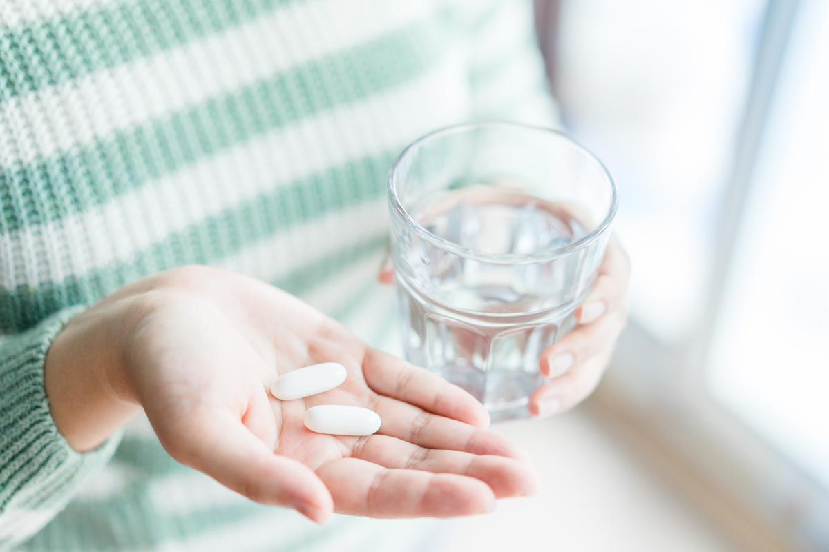 A woman taking a few supplements.