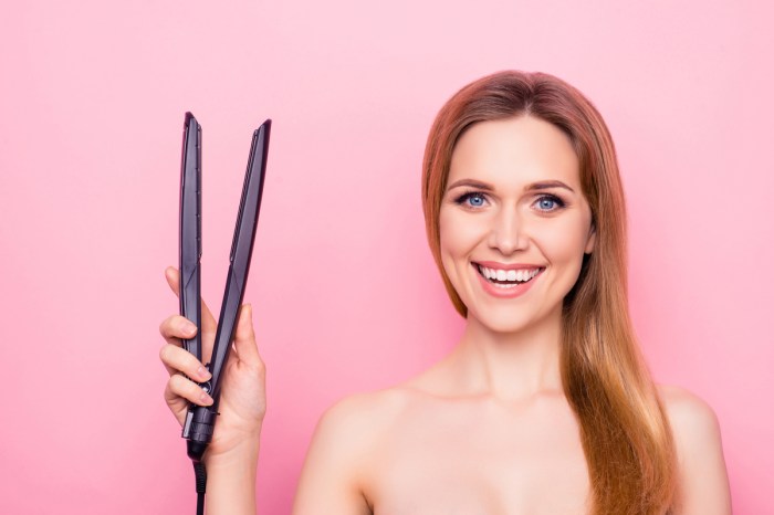 A woman holding up a flat iron hair straightener.