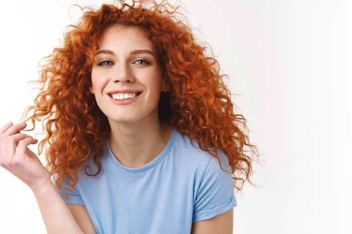 A woman with red curly hair wearing a blue shirt.