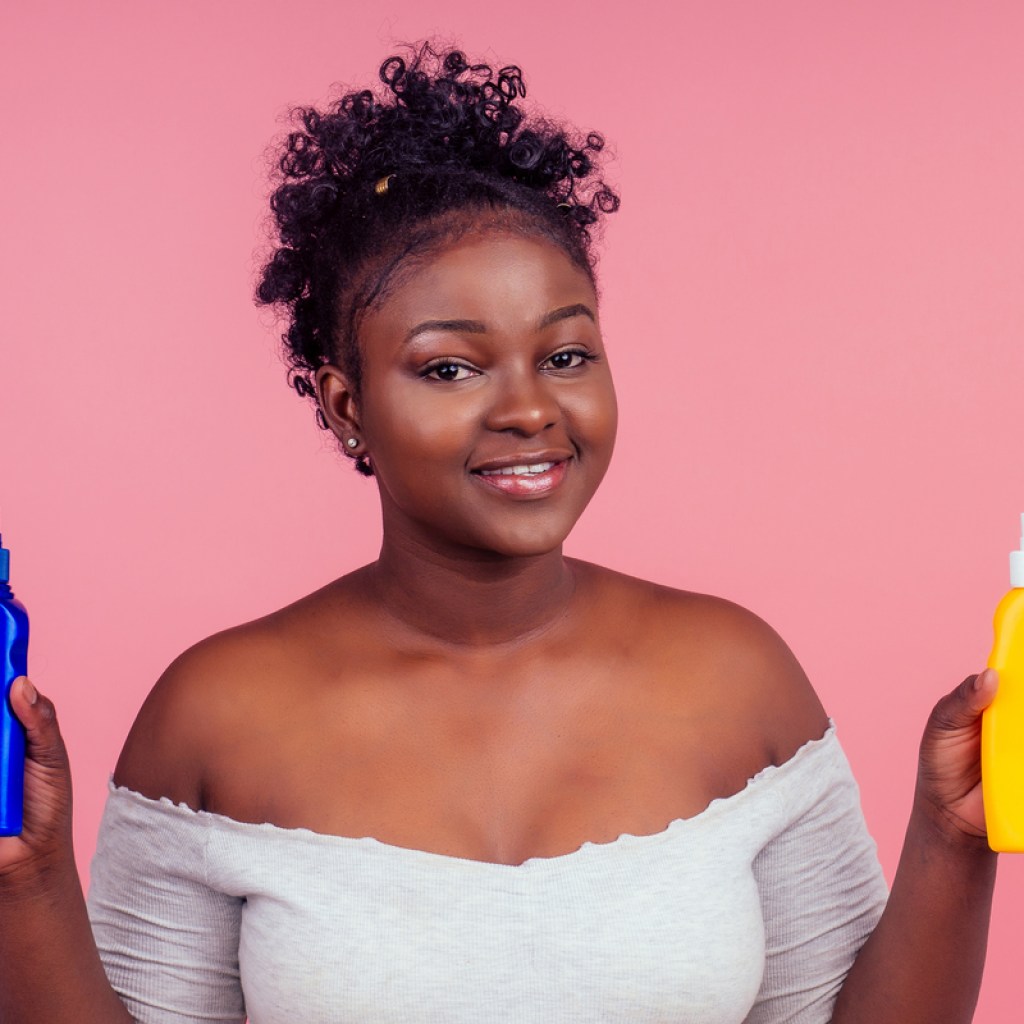 A Black woman holding beauty products in her hands.
