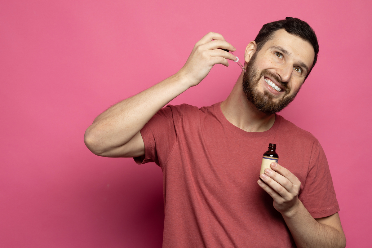A man putting beard oil on his face.