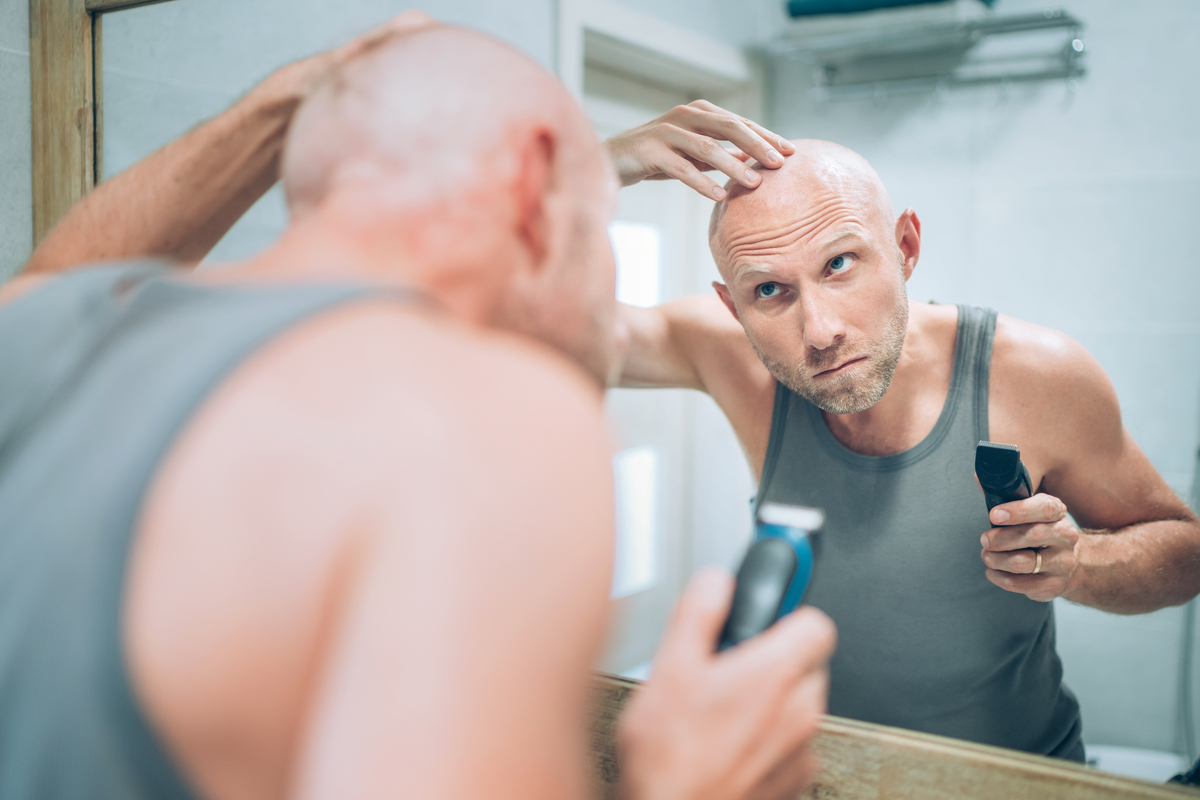 A man checking his shaved head in the mirror.