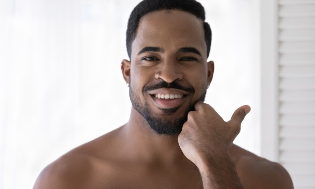A man rubbing his hand along his beard.