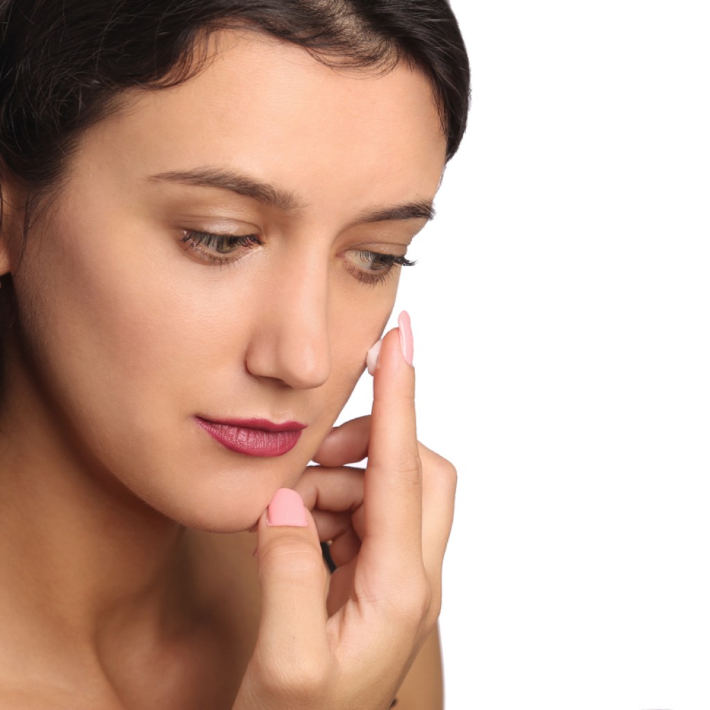 A woman putting on primer before adding her makeup.