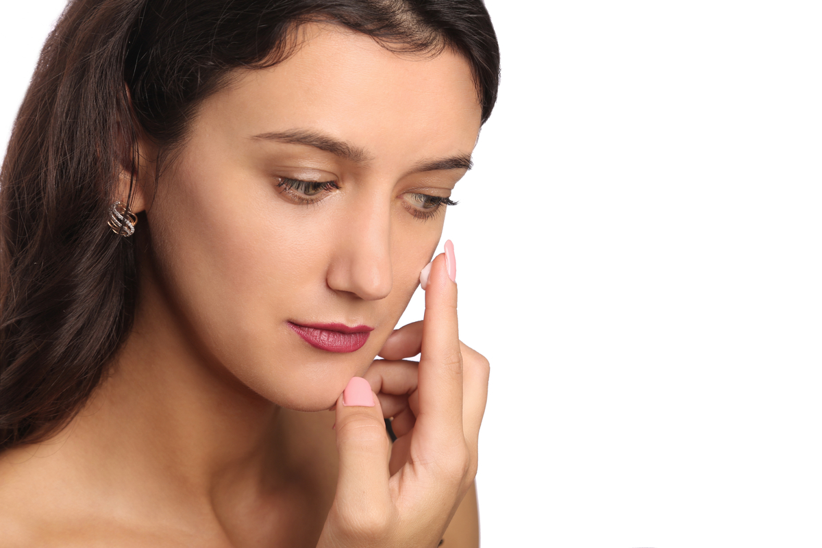 A woman putting on primer before adding her makeup.