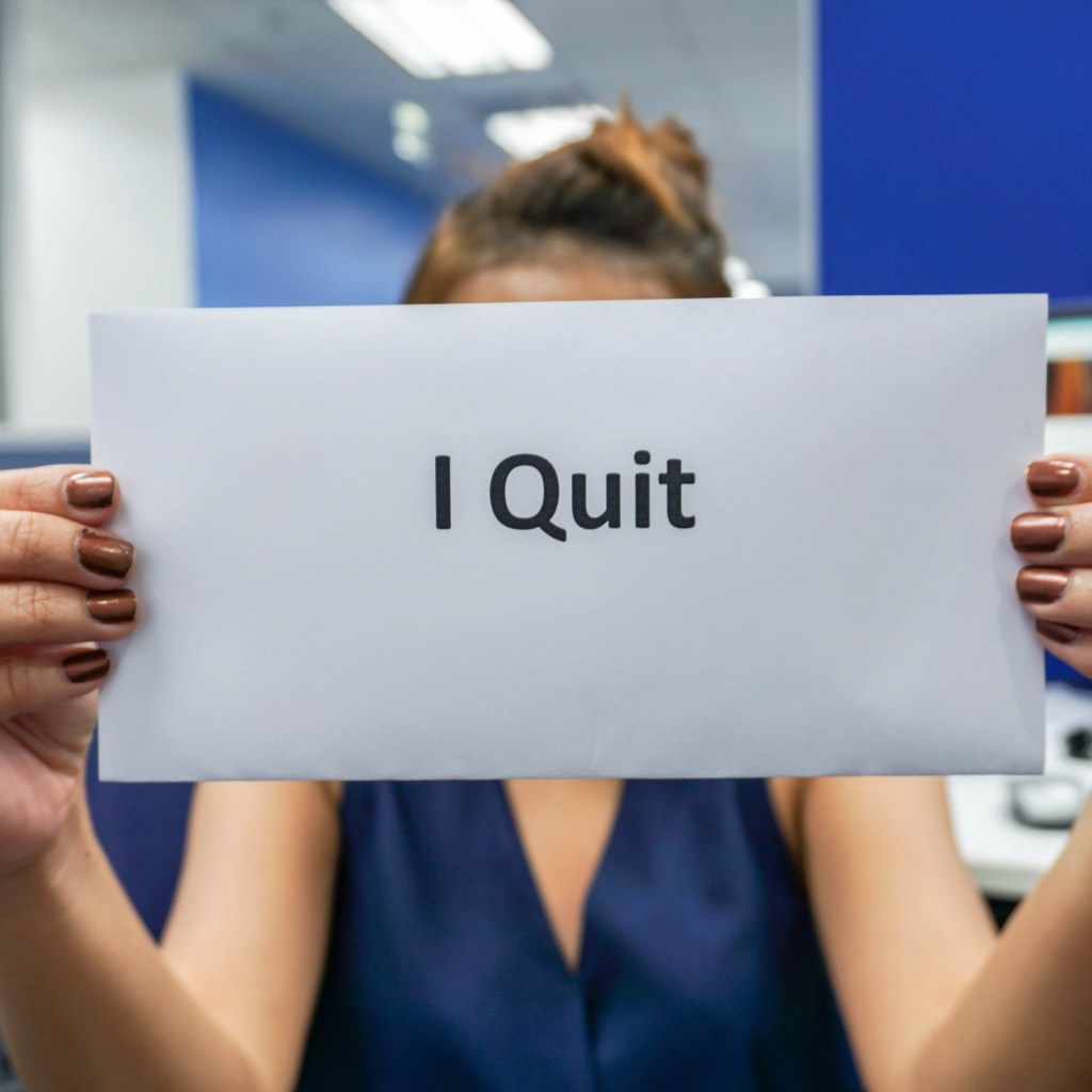 Closeup of woman's hands holding envelope that says "I quit"