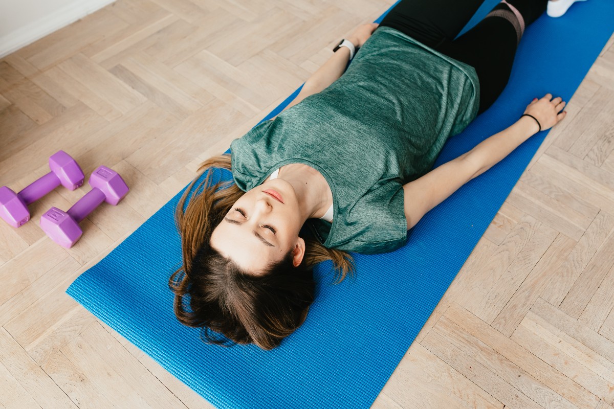 woman in savasana pose on blue yoga mat