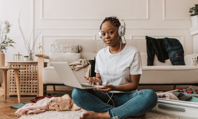 a woman sitting on the floor listening to music while on the computer