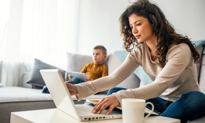 Woman sitting on couch working on laptop hunched over coffee table