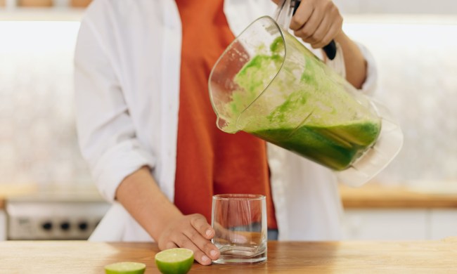Woman pouring green smoothie into a cup