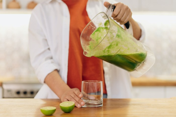 Woman pouring green smoothie into a cup