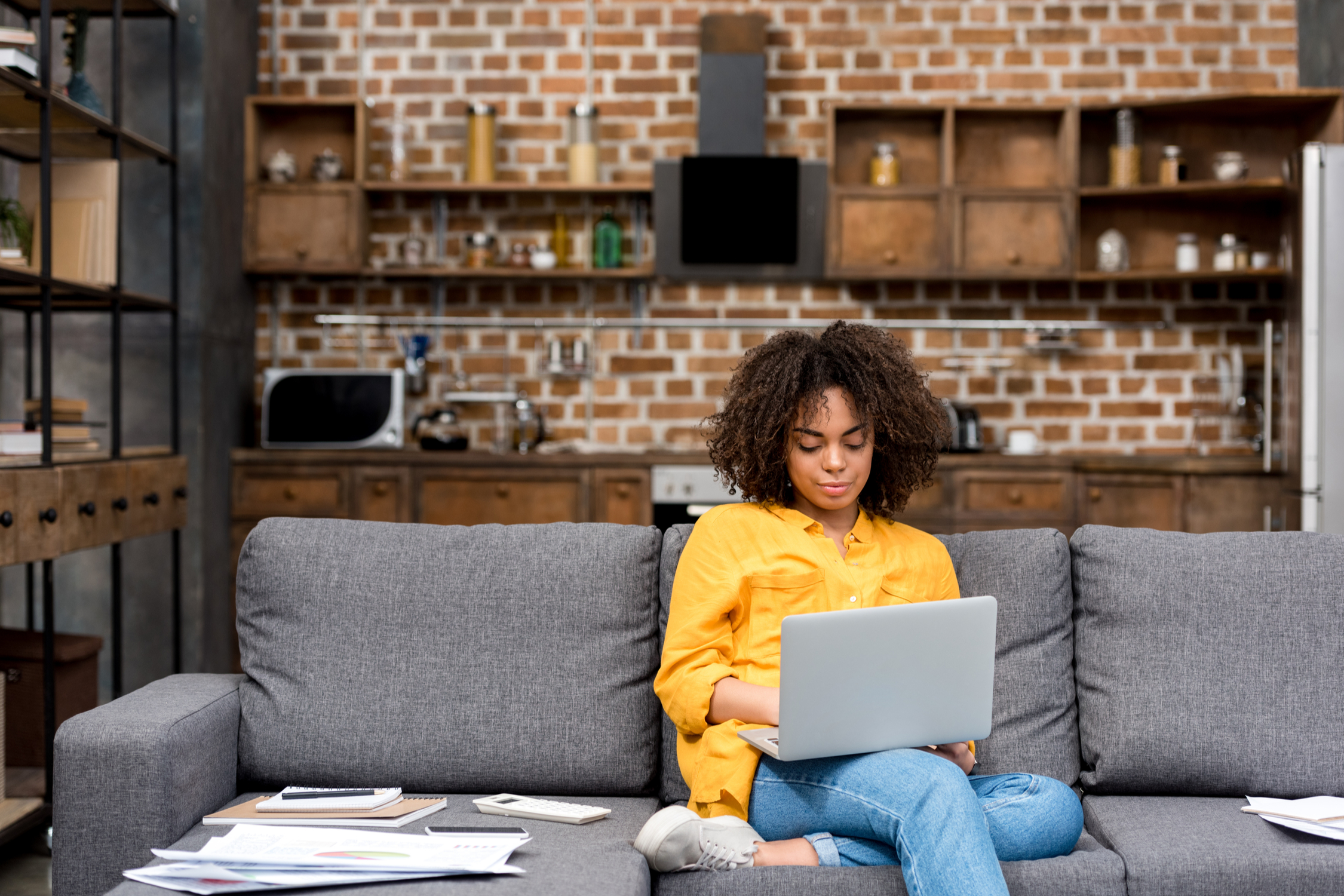 woman working while sitting on couch with laptop on lap