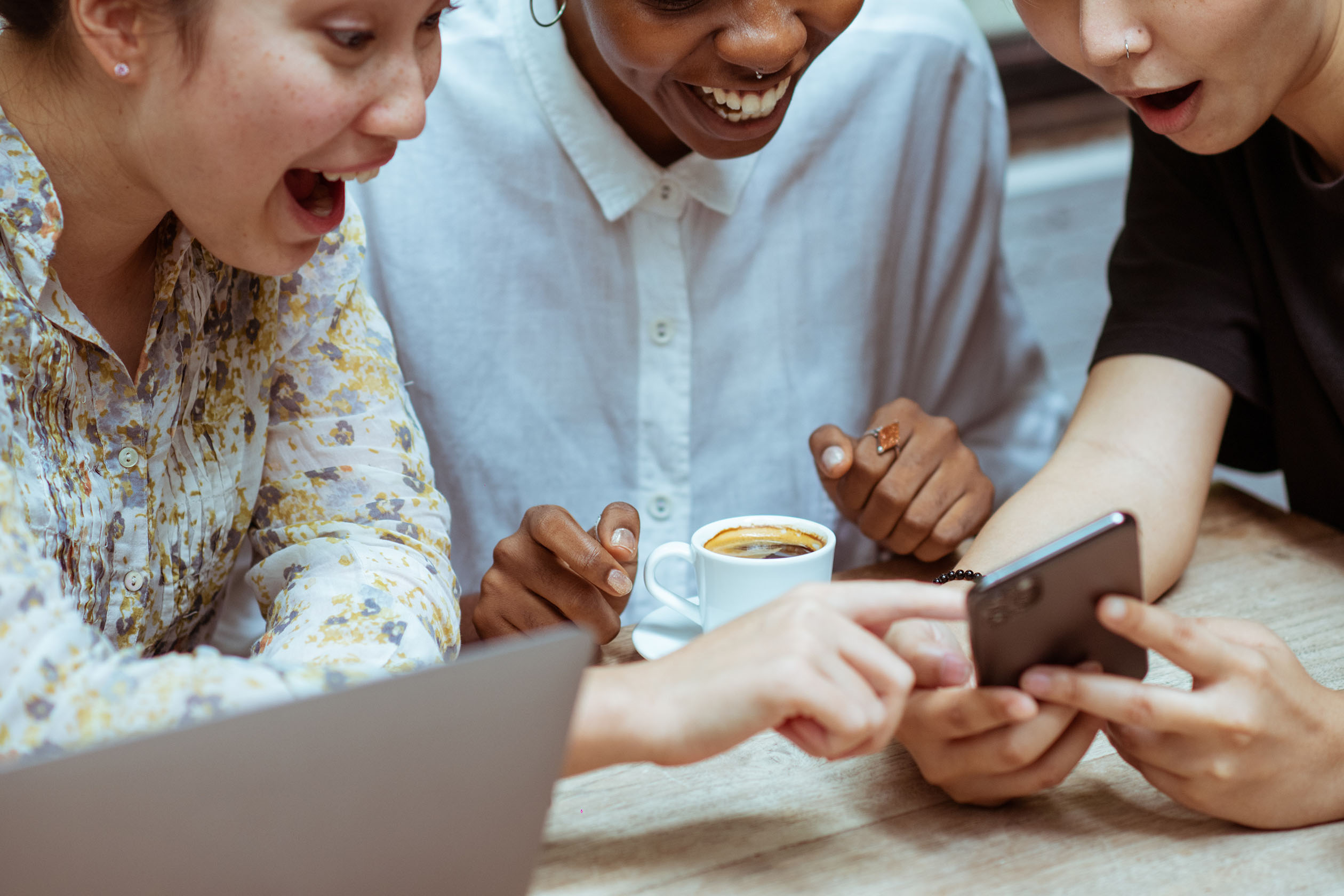 Group of friends looking at a phone with surprise and joy