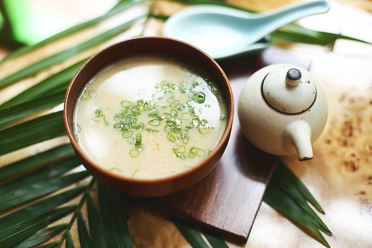 a small bowl of miso soup next to a teapot