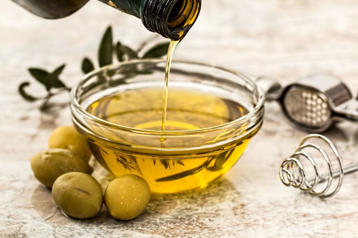 Olive oil pouring into a bowl with olives