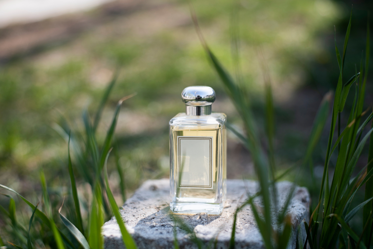 a fragrance bottle sitting on a stone in the grass.