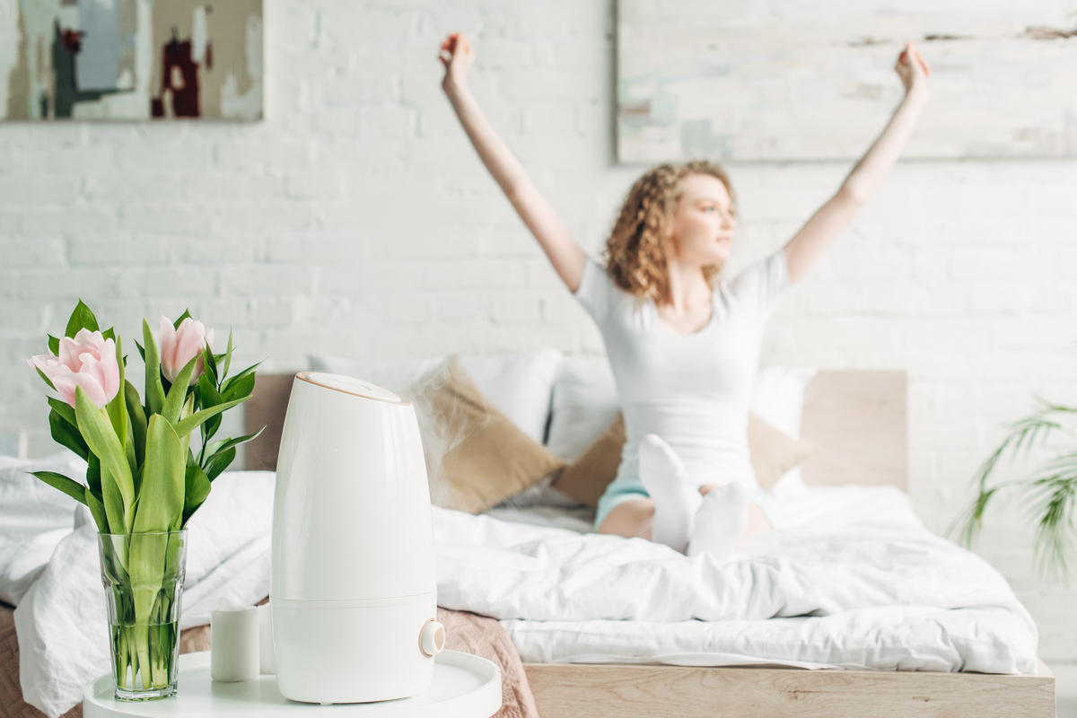 A woman waking up with an air purifier in her room.