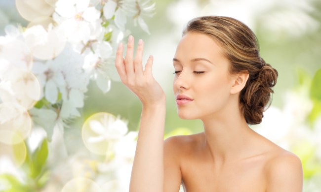 A woman smelling the scent on her wrist.