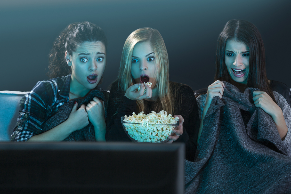 Three women watching a scary movie.
